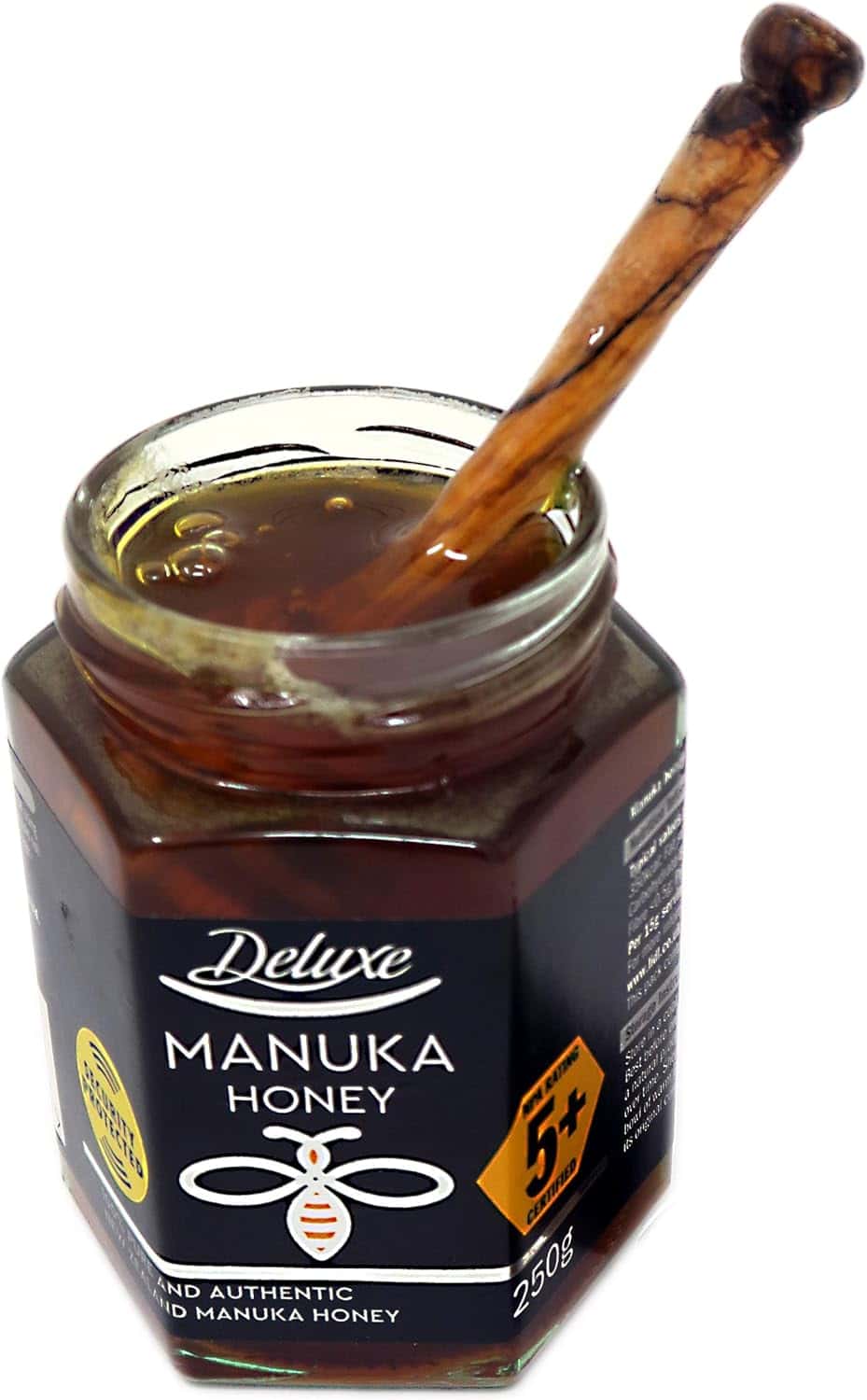 An olive wood honey dipper resting in an open jar of honey