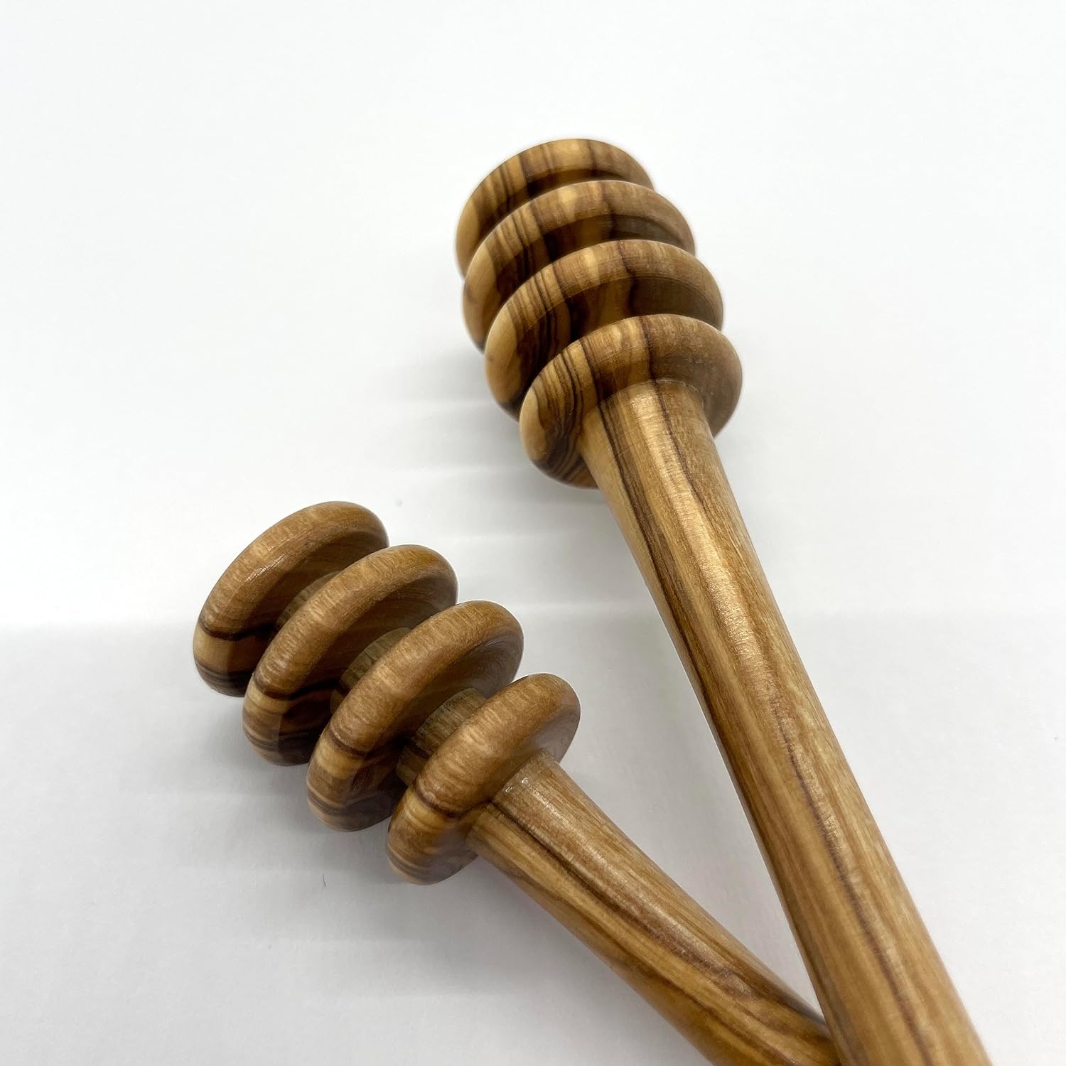 Close up of two olive wood honey drizzlers showing their turned ridges